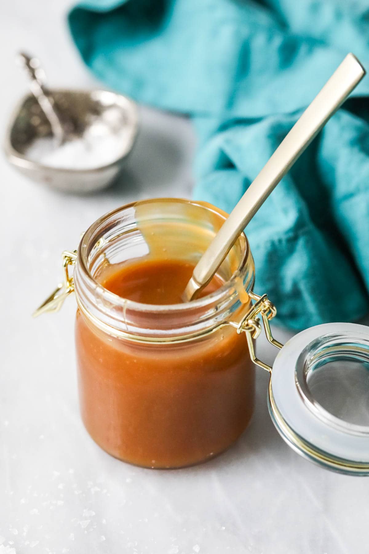 Spoon resting in a jar of caramel sauce.
