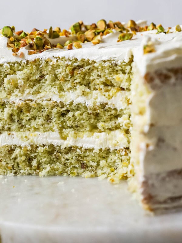 Cross section of a pistachio cake made with three layers of green cake and a swiss meringue buttercream frosting.