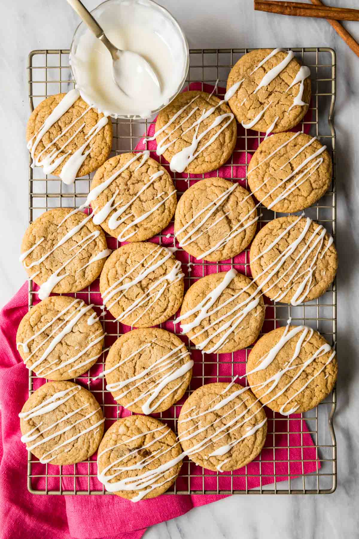Overhead view of spice cookies topped with a vanilla glaze drizzle on a cooling rack.
