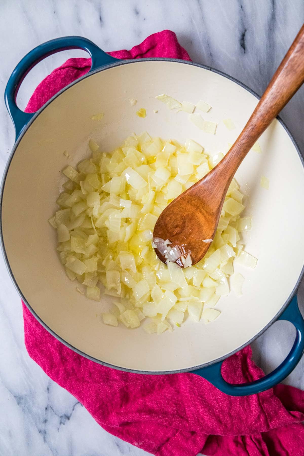 Overhead view of chopped onions cooking in a pot.