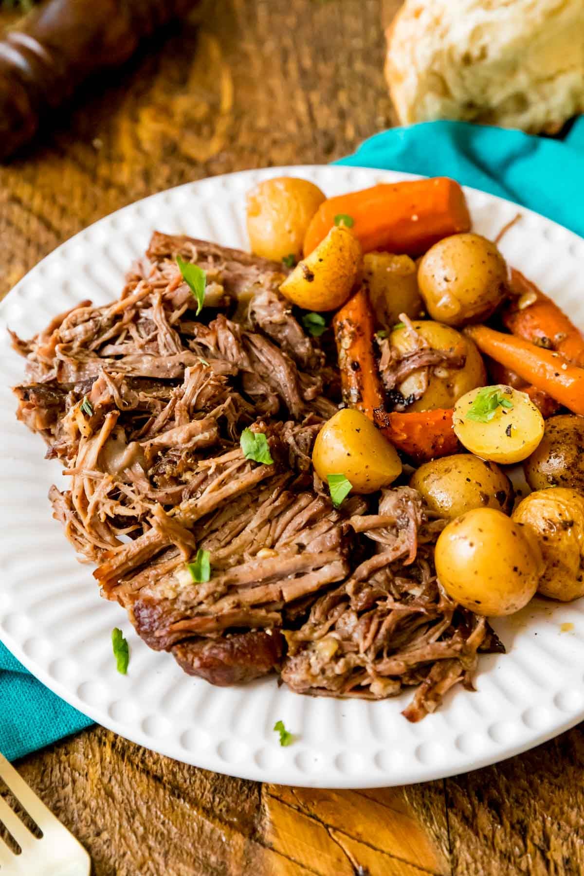 white plate full of my best pot roast recipe with baby potatoes and carrots.