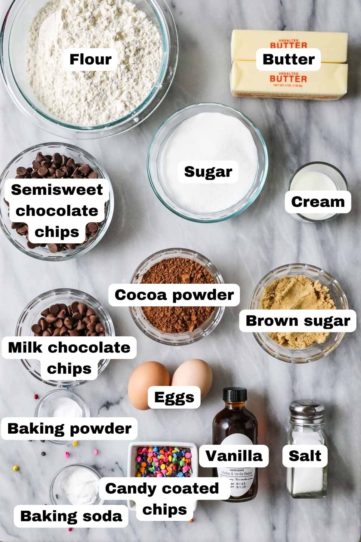 Overhead view of labelled ingredients including cocoa powder, chocolate chips, candy pieces, and more.