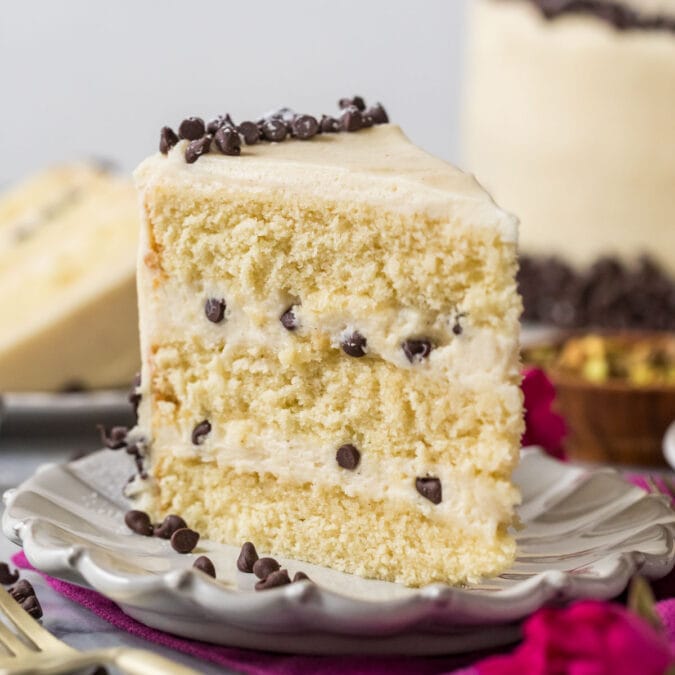 Slice of cannoli cake standing on a white plate.