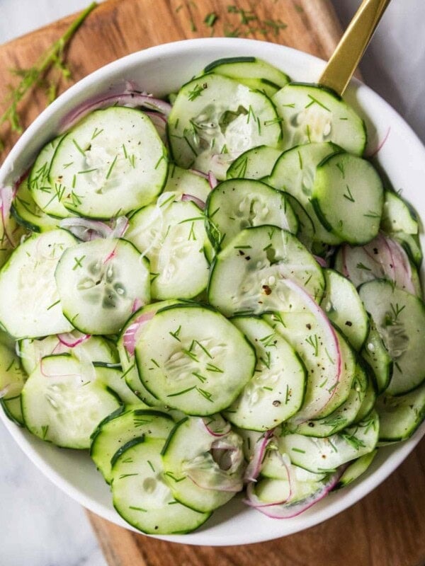 Overhead view of a serving bowl of cucumber salad made with dill and red onion.