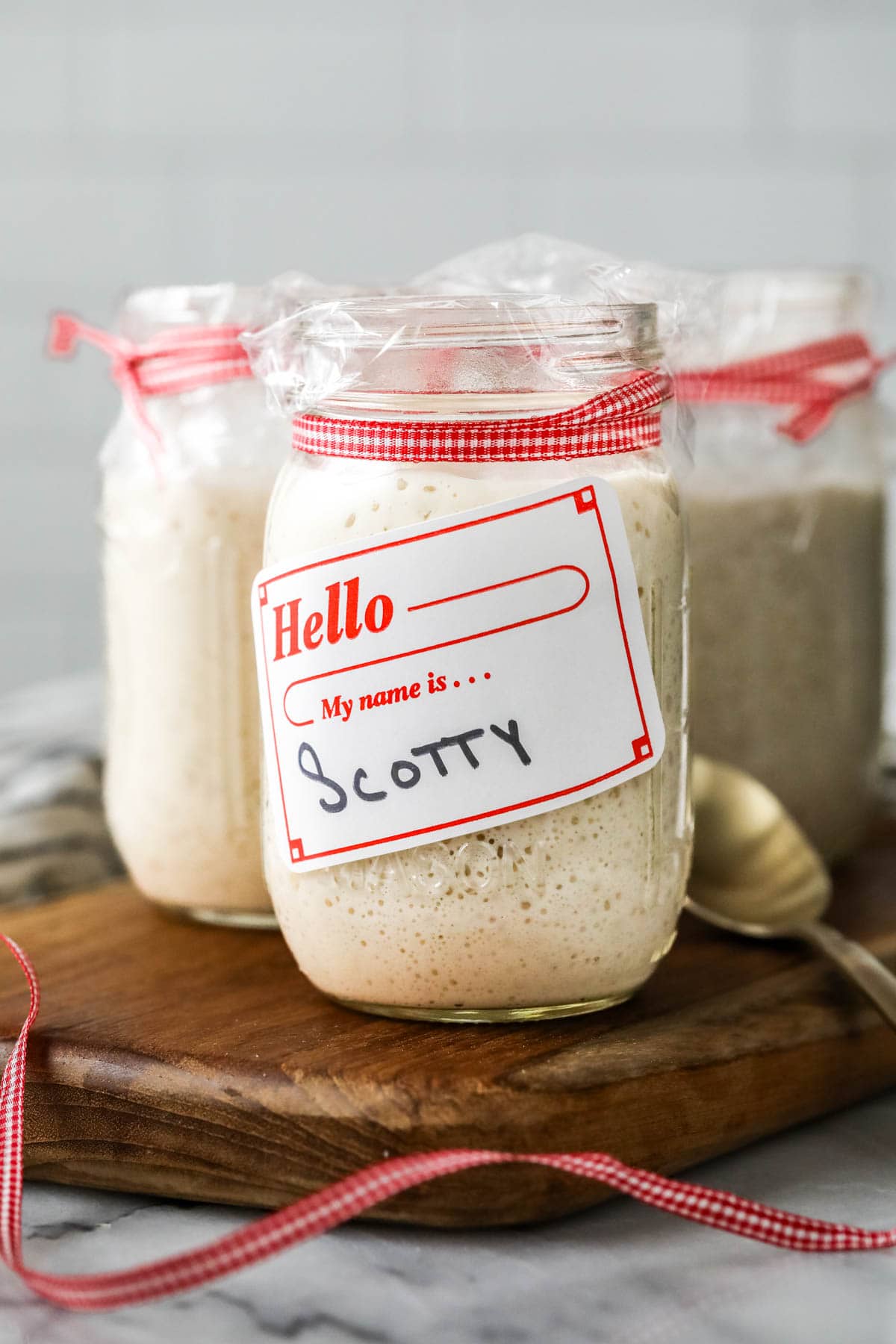 Jar of active sourdough starter with a nametag on it reading "Scotty"