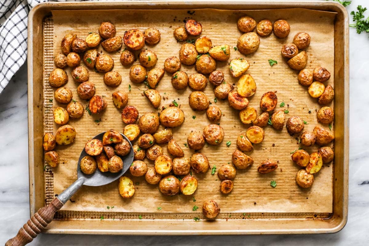 Overhead view of a sheet pan of small potatoes that have been roasted in the oven.