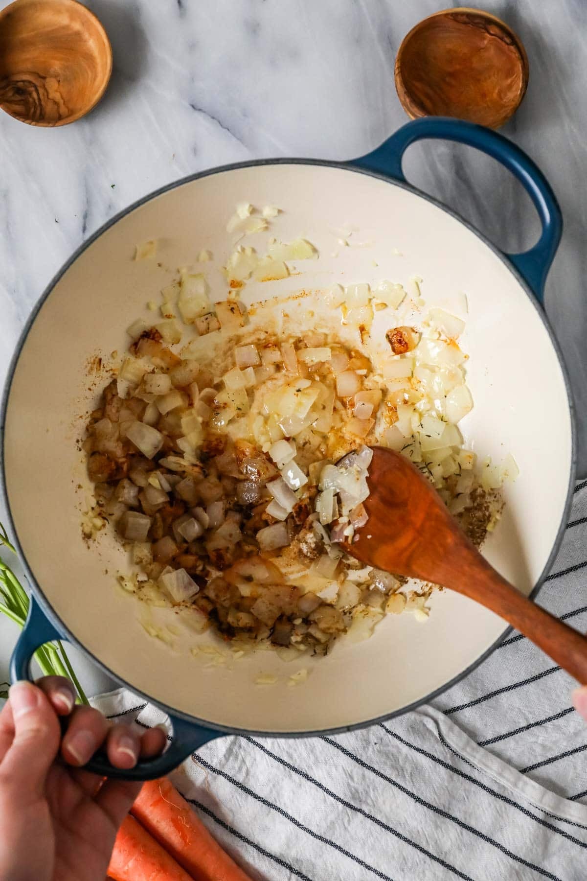 Overhead view of a dutch oven with onions and spices sauteing inside.