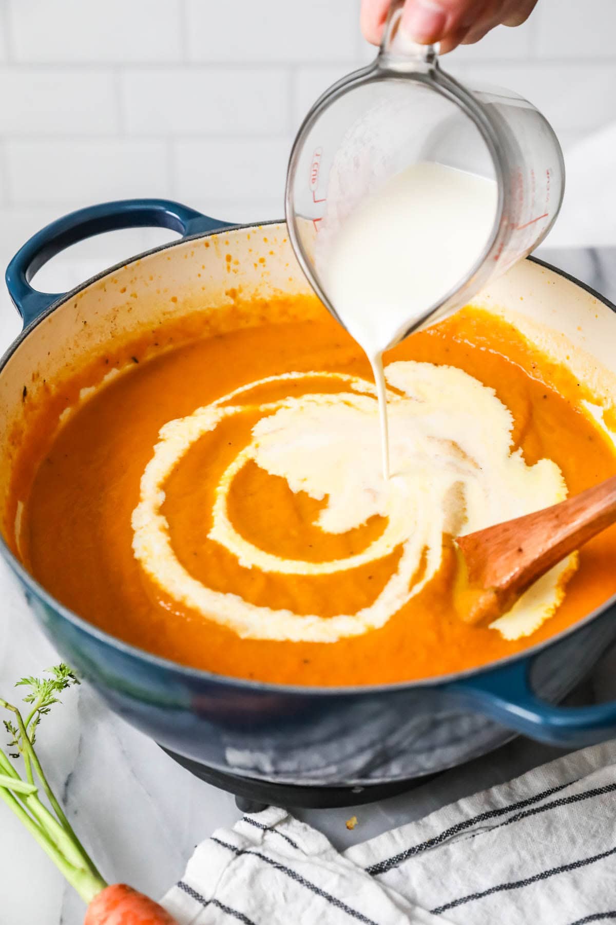 Cream being poured into a carrot soup.