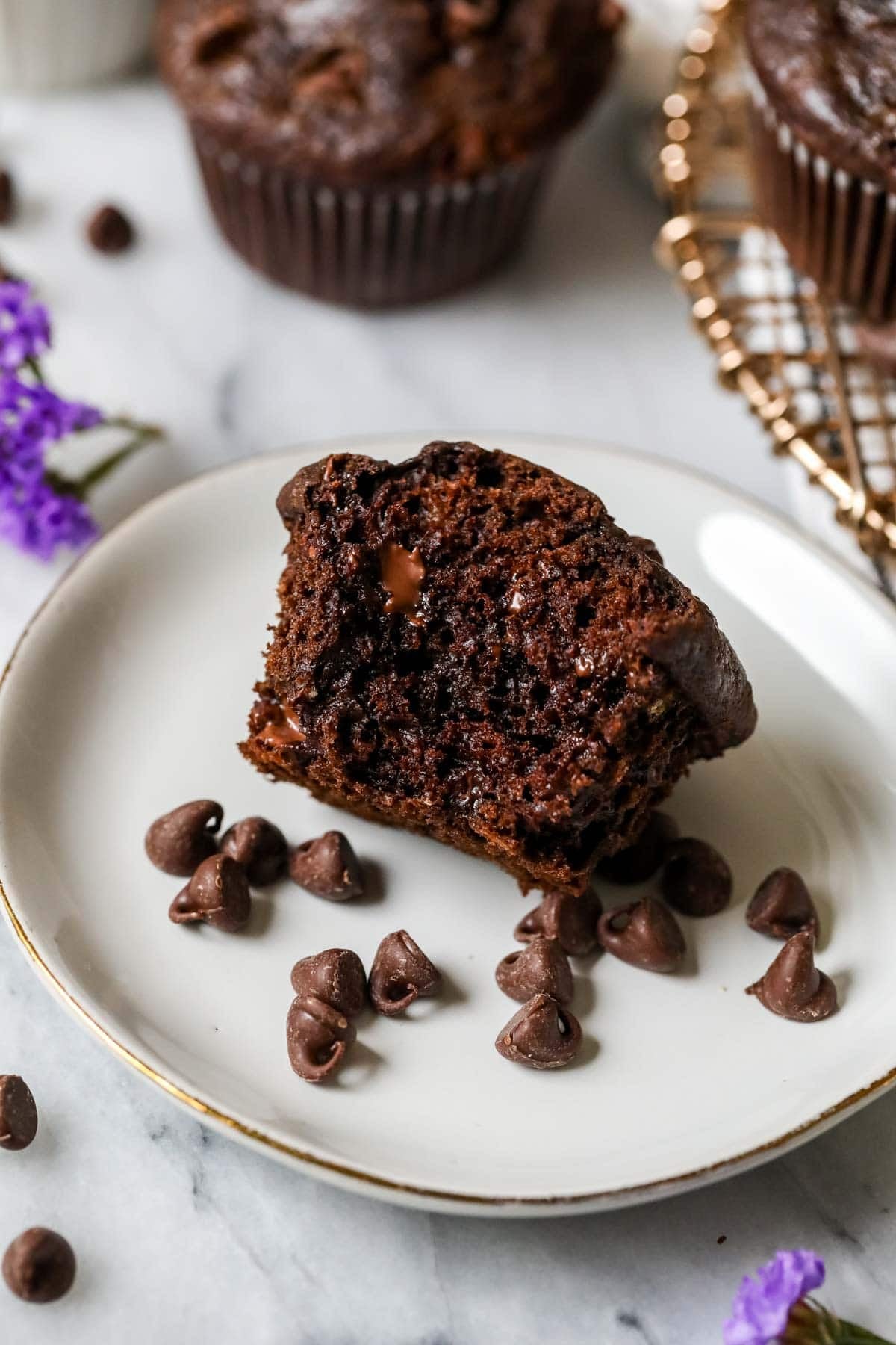 Bite missing from a chocolate muffin made with banana and chocolate chips.