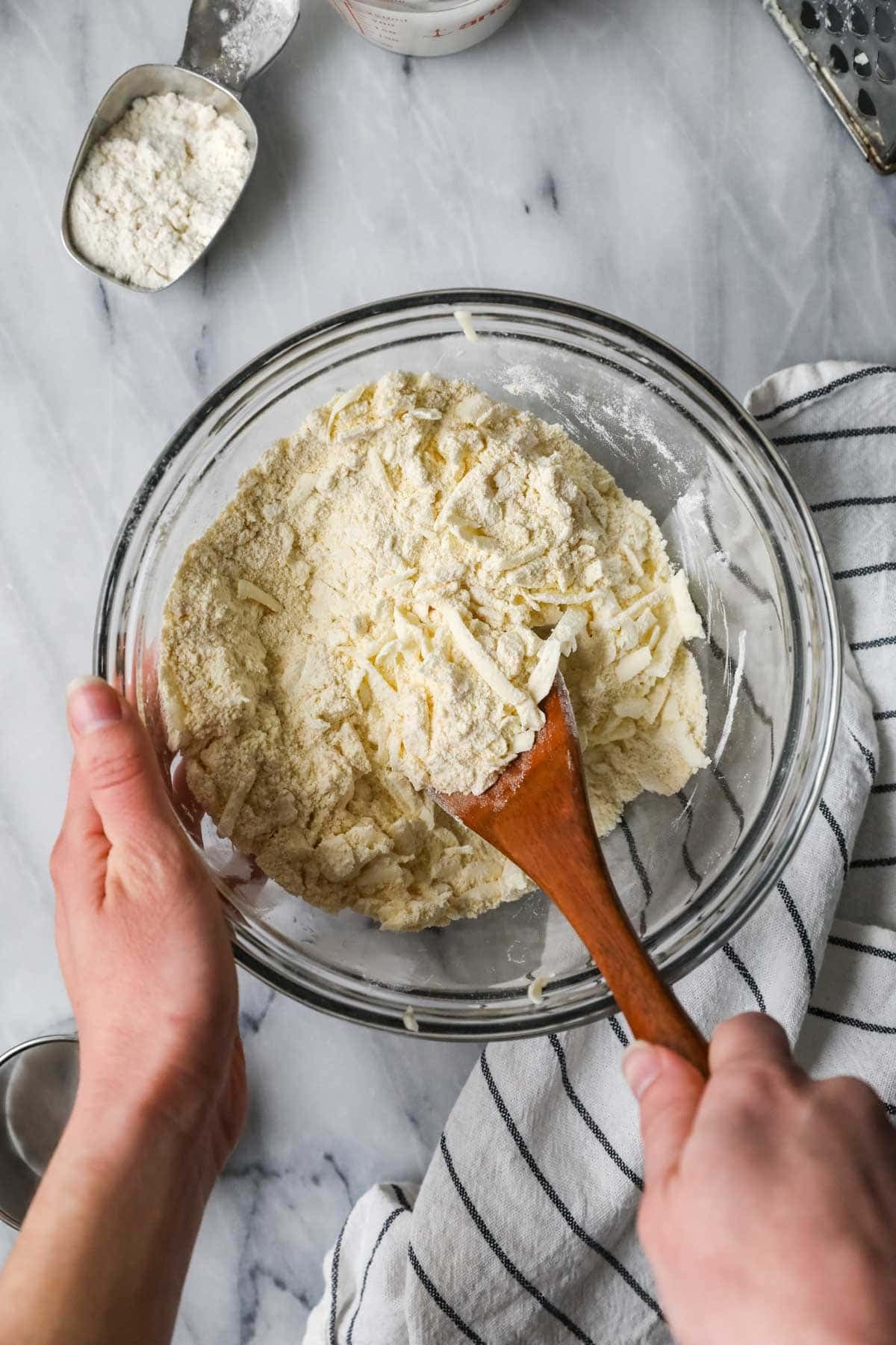 Overhead view of butter shreds being stirred into a cornmeal mixture.
