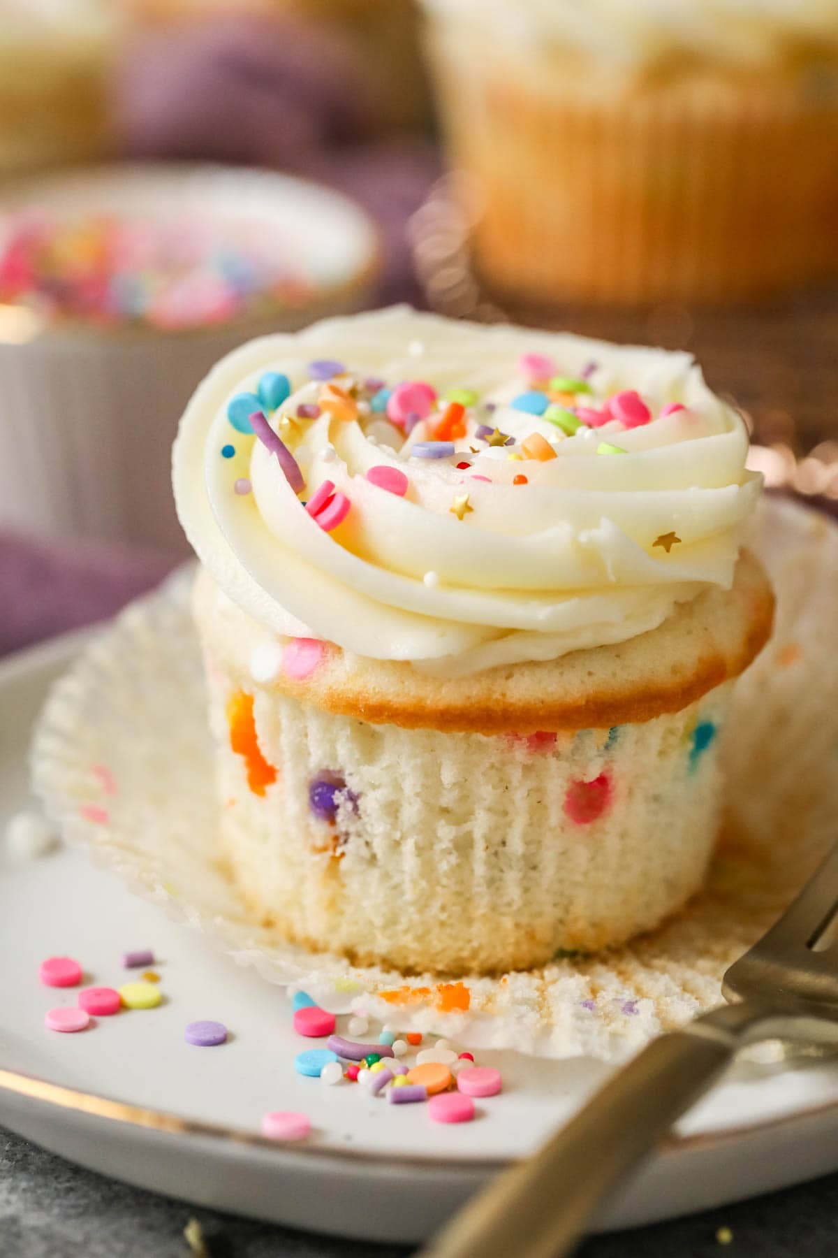 Cupcake made with sprinkles in the batter and on top of the frosting.
