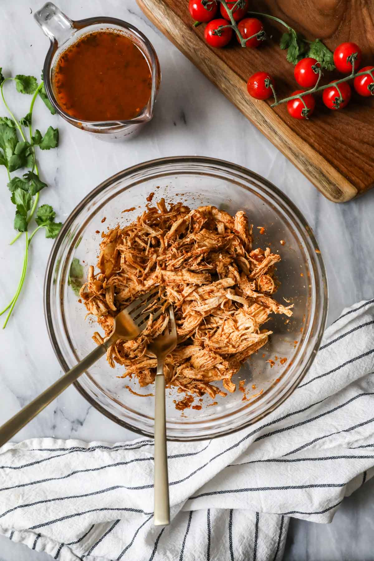 Overhead view of a bowl of shredded seasoned chicken breast.