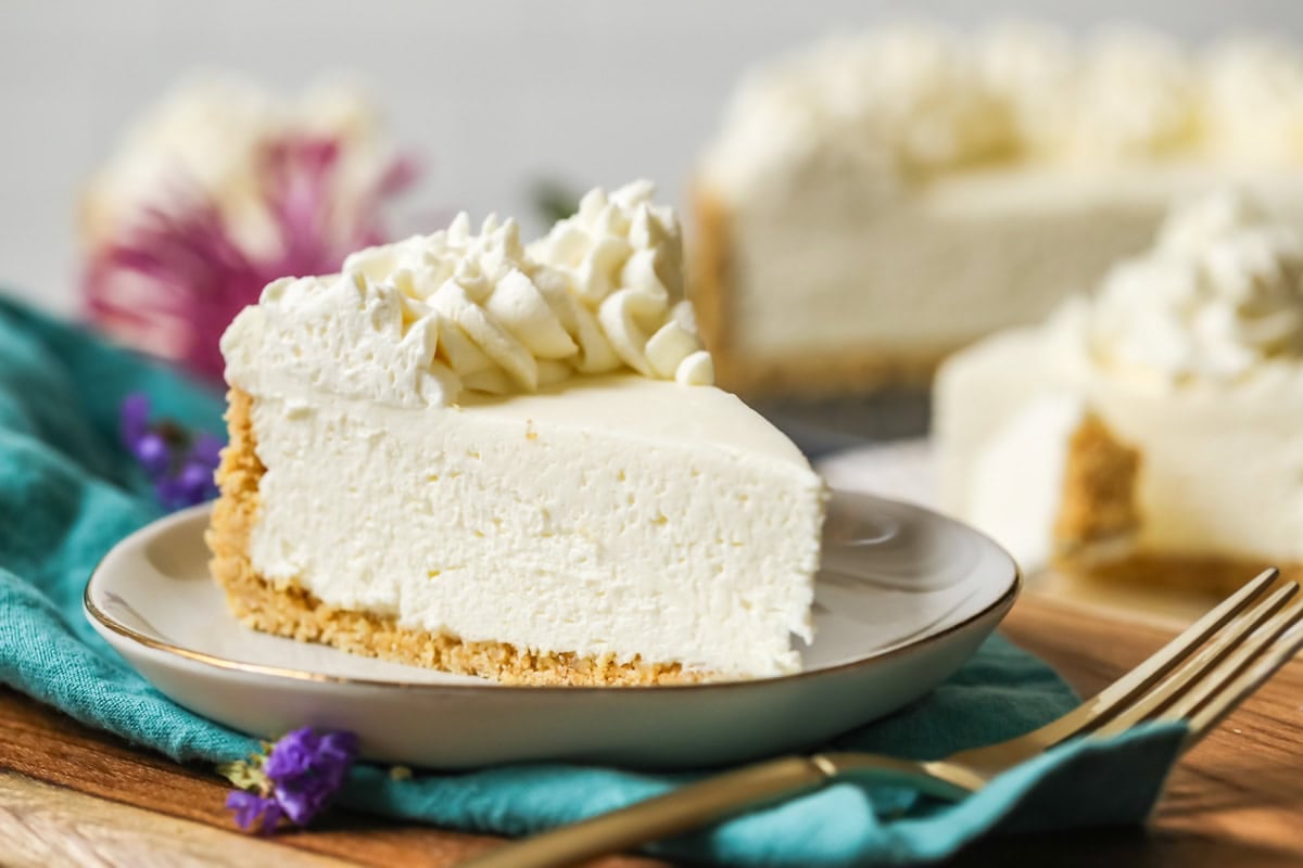 Slice of no-bake cheesecake with a whipped cream topping on a plate.