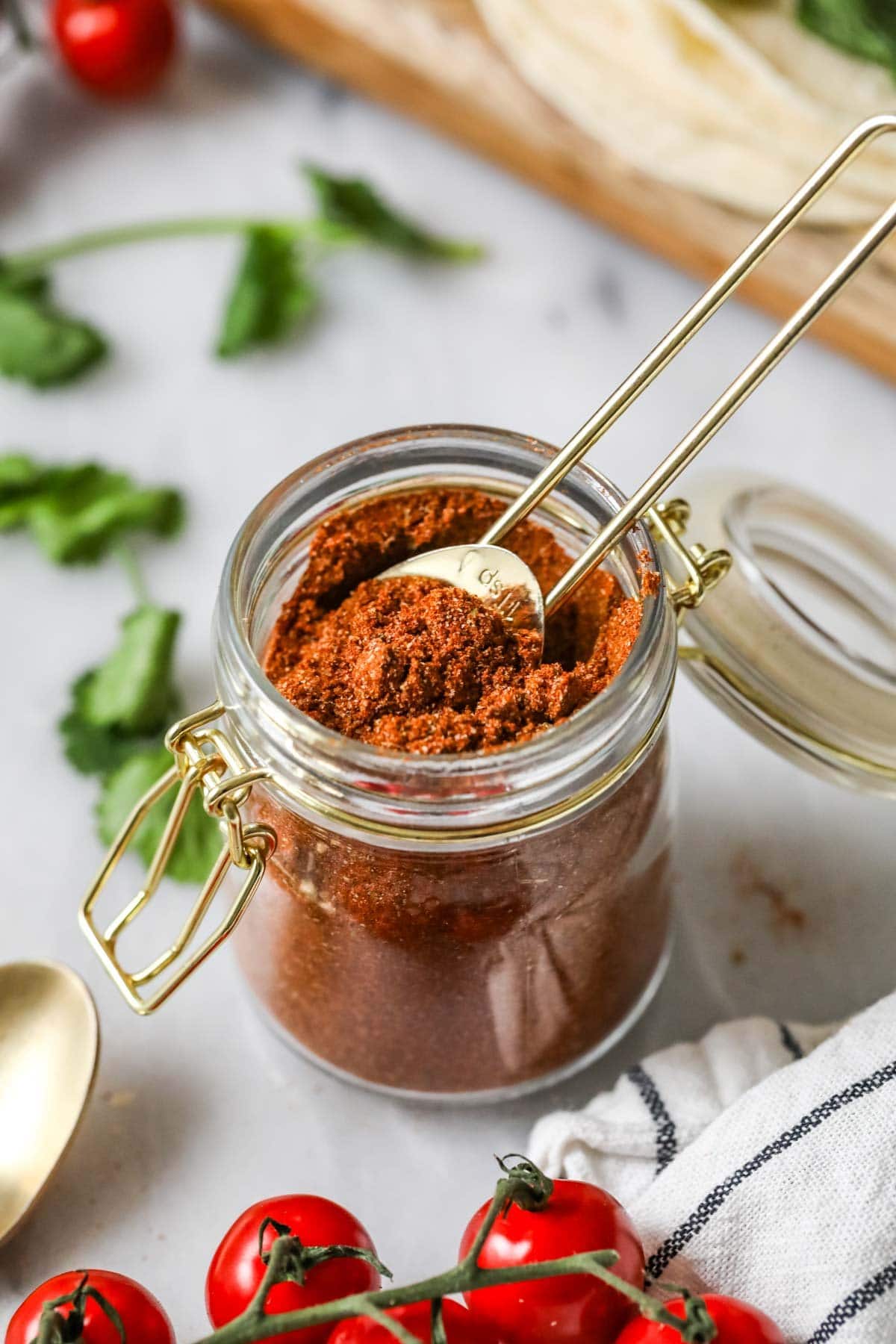 Teaspoon scooping from a jar of taco seasoning made from a homemade taco seasoning recipe. 