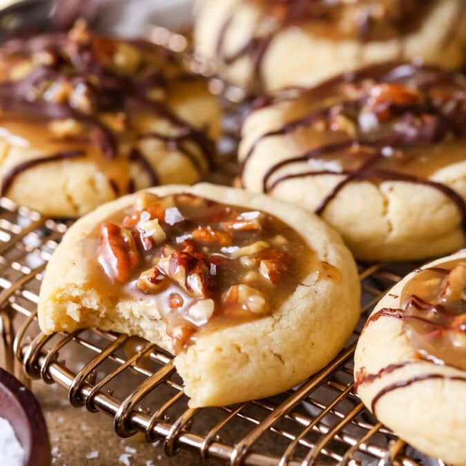 Pecan pie cookies on a cooling rack with the front cookie missing a bite.