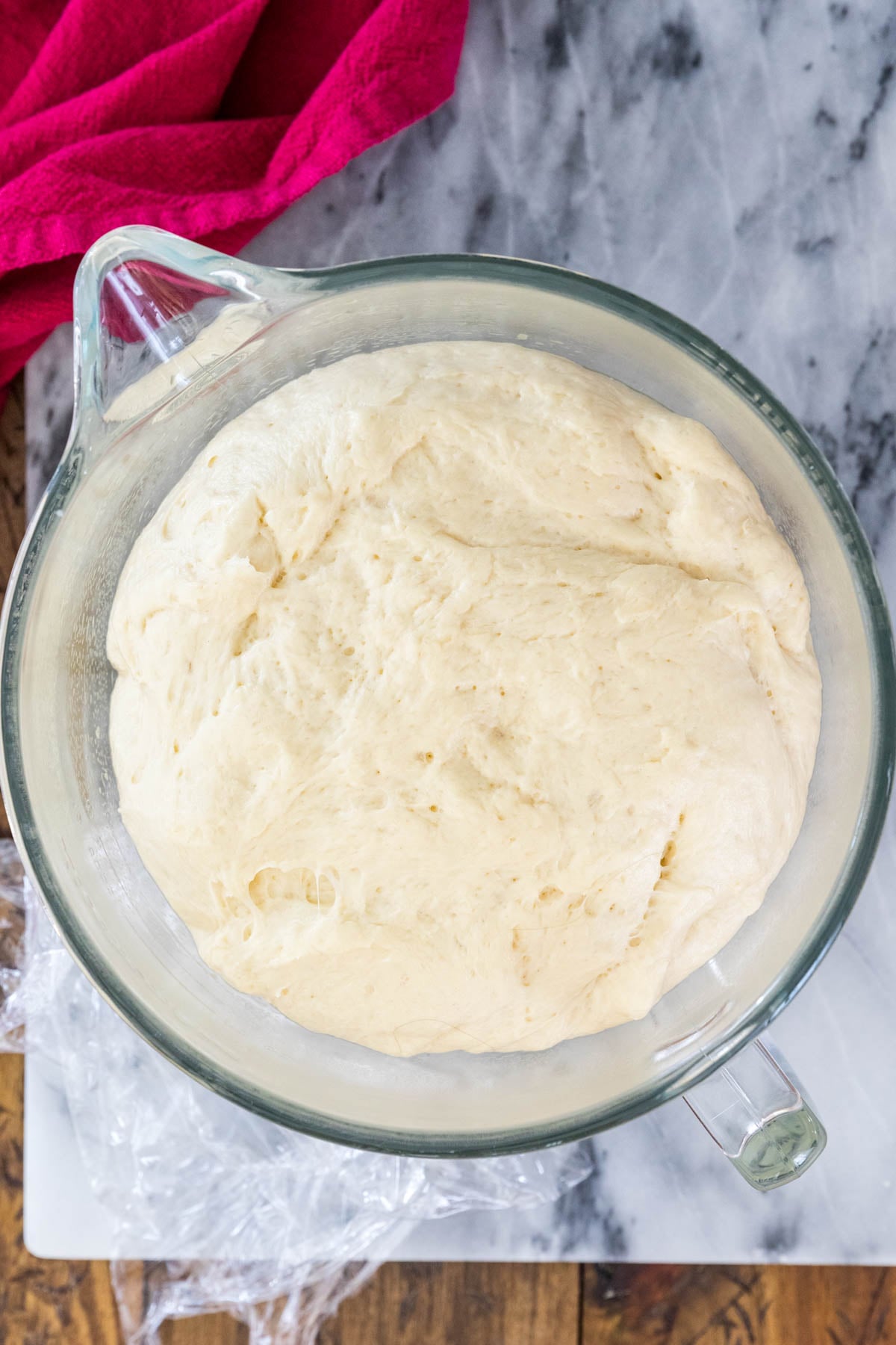 Risen sticky bun dough in glass mixing bowl.