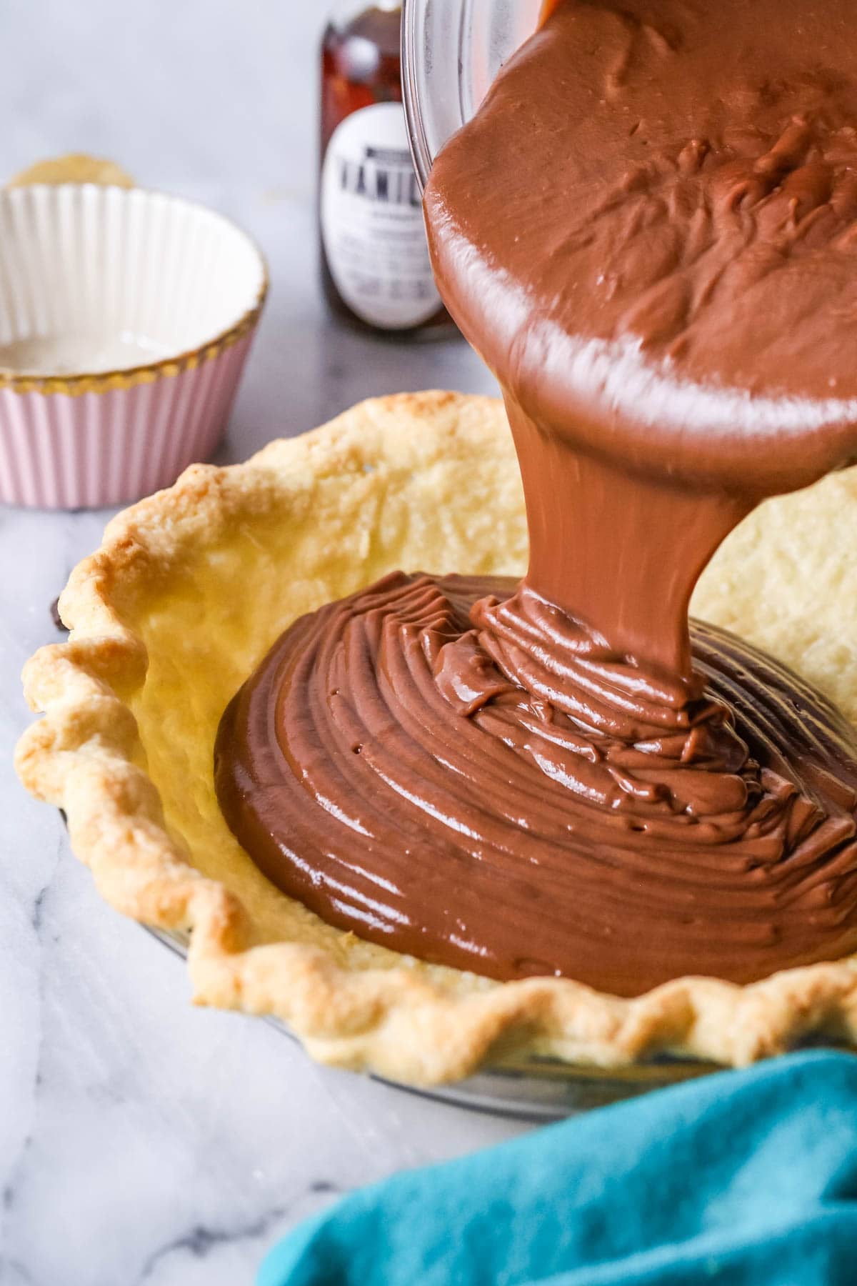 Pouring chocolate pie filling into a prepared crust.