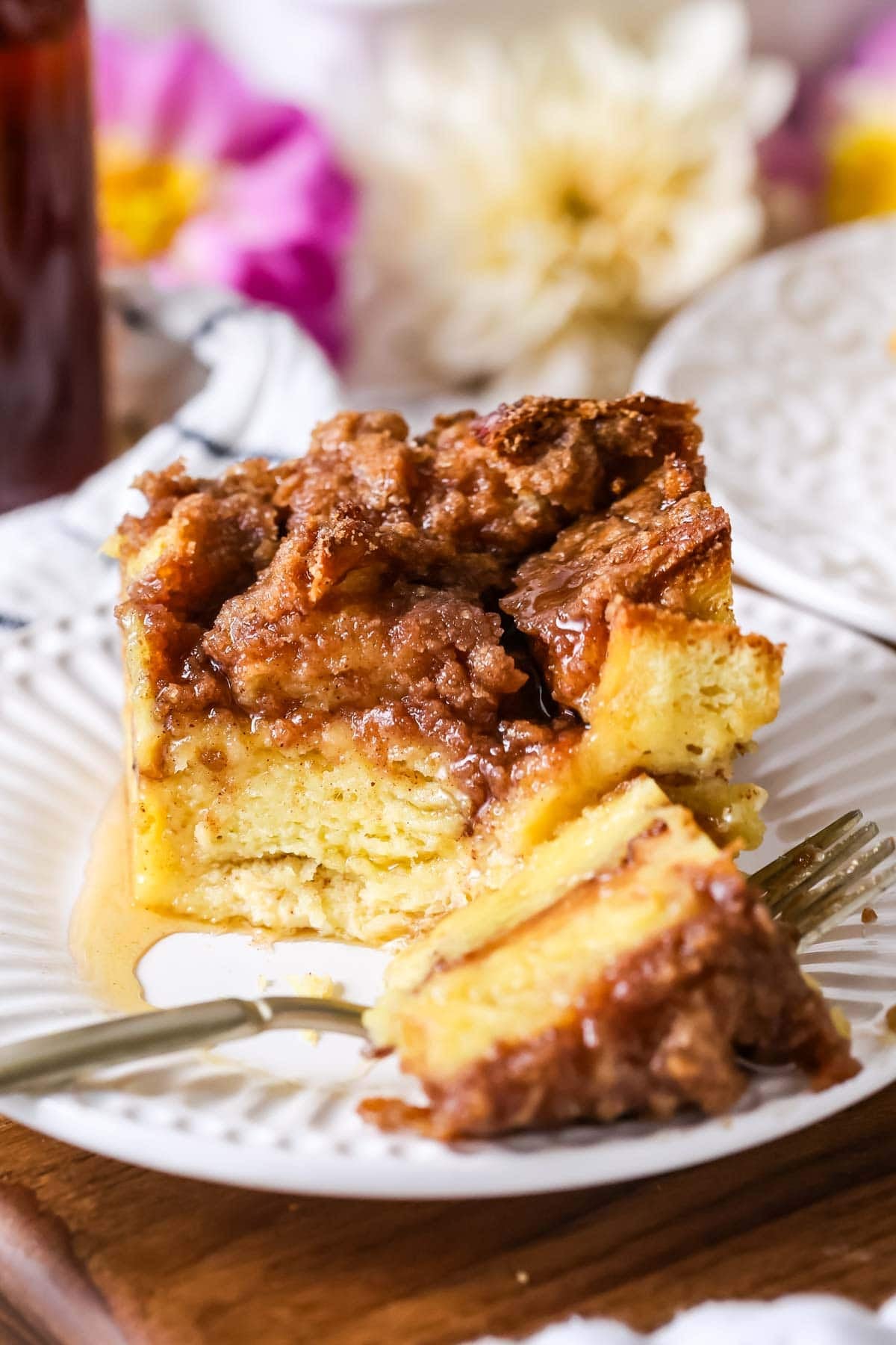 Serving of French toast casserole on a plate with one bite on a fork.