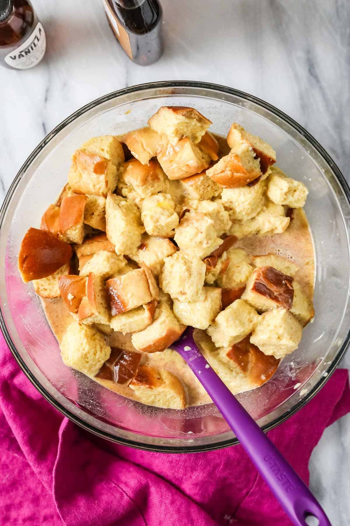 Overhead view of a bowl of challah bread cubes soaking in a custard mixture.