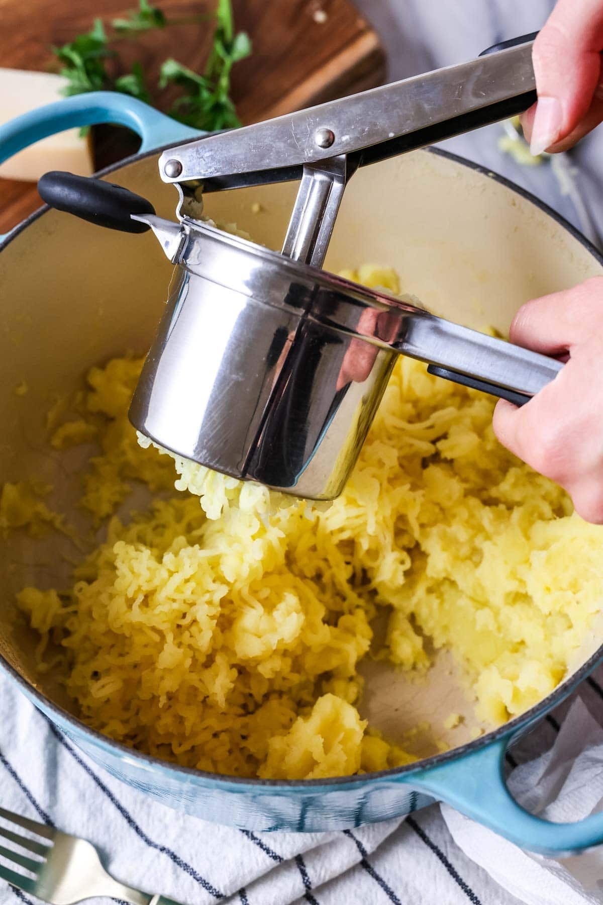 Potatoes being pushed through a ricer for a fine texture.