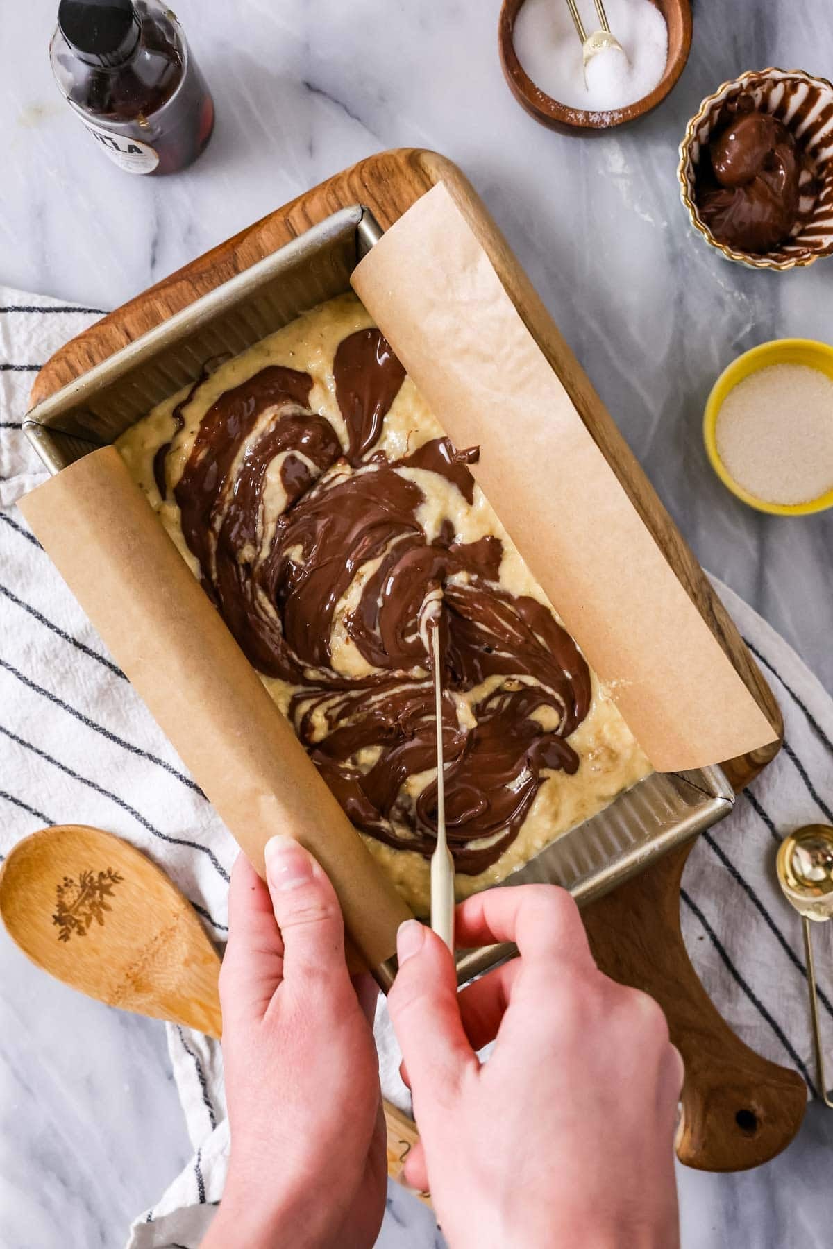 Overhead view of a nutella filling being swirled into banana bread batter.