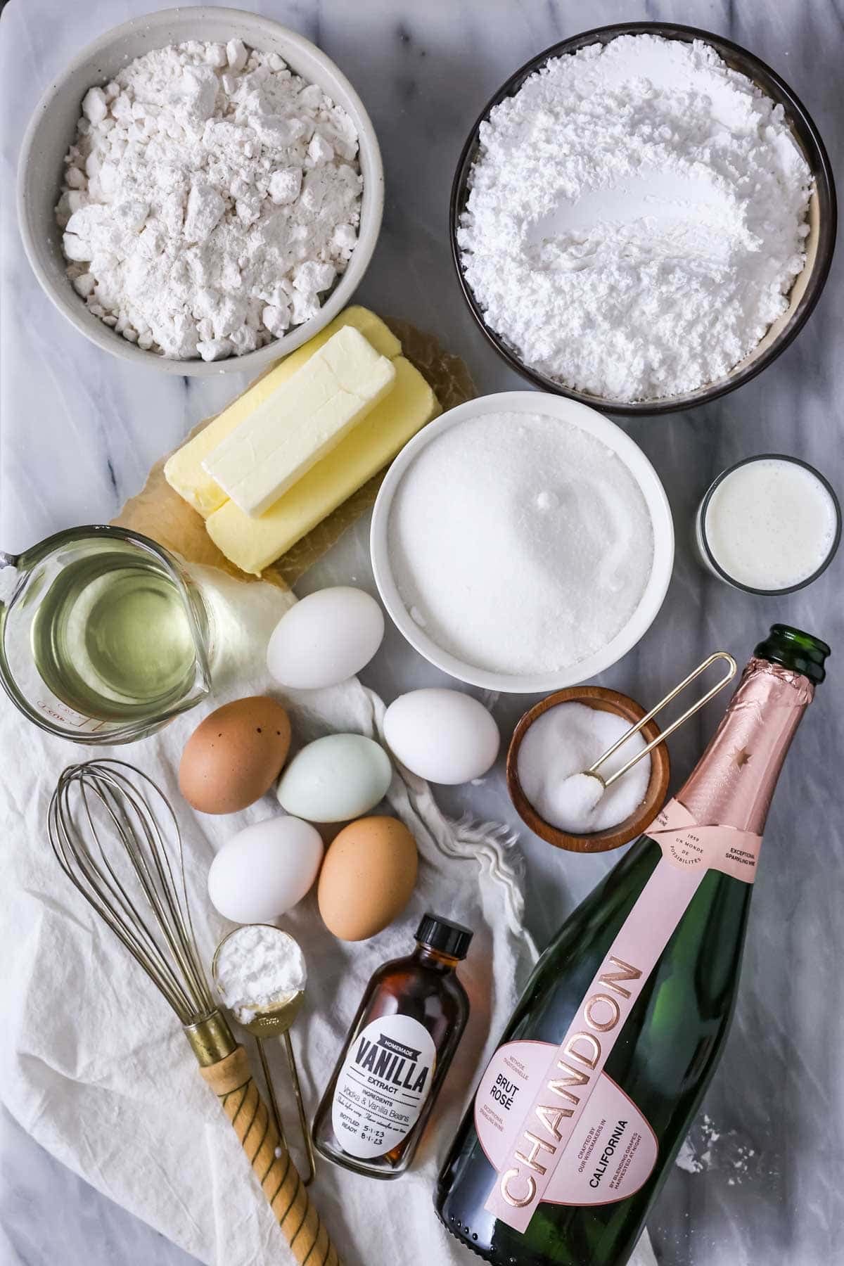 Overhead view of ingredients including pink champagne, butter, eggs, and more.
