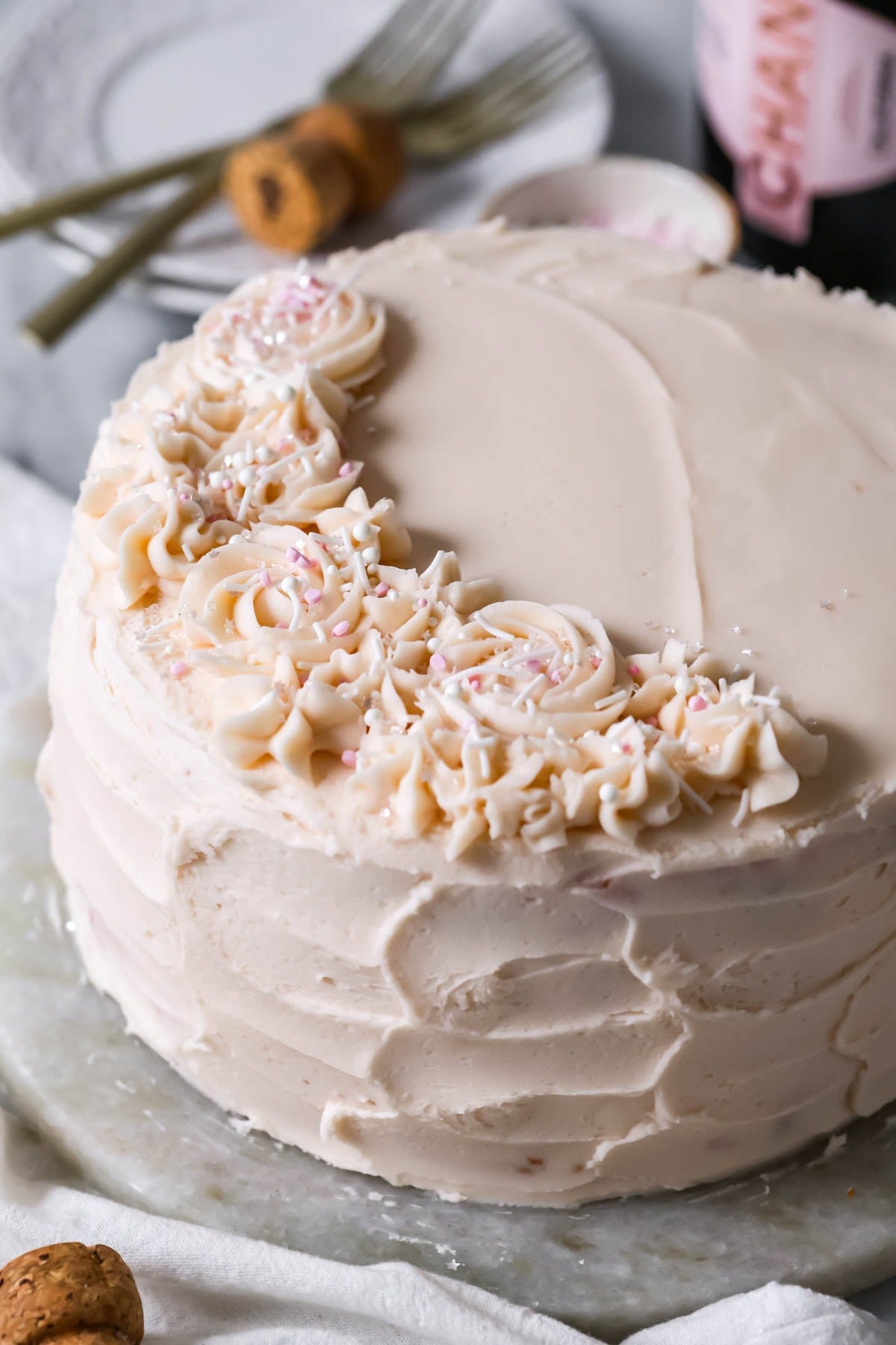 Cake frosted with a pale pink frosting and piped icing flowers on one edge.