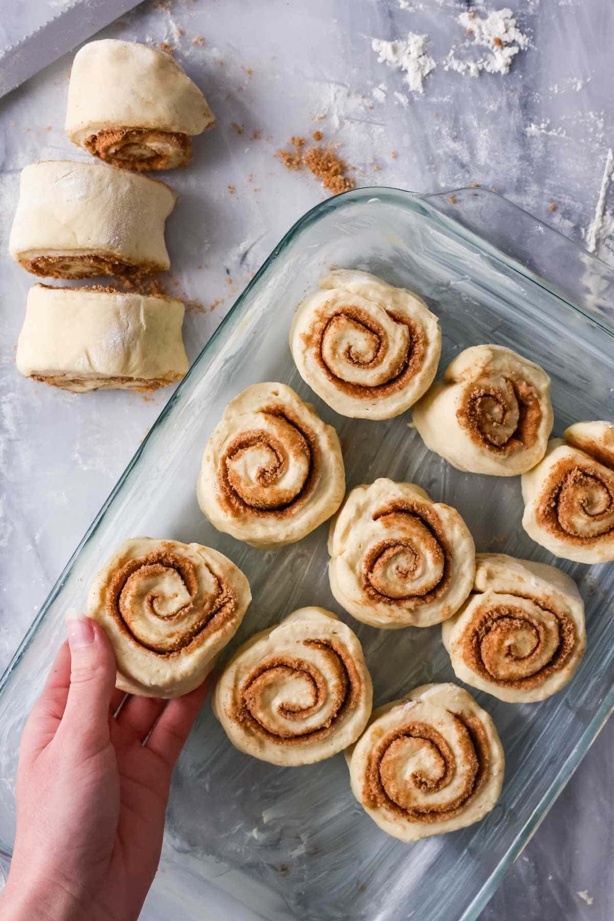 Placing cut cinnamon roll dough into pan..