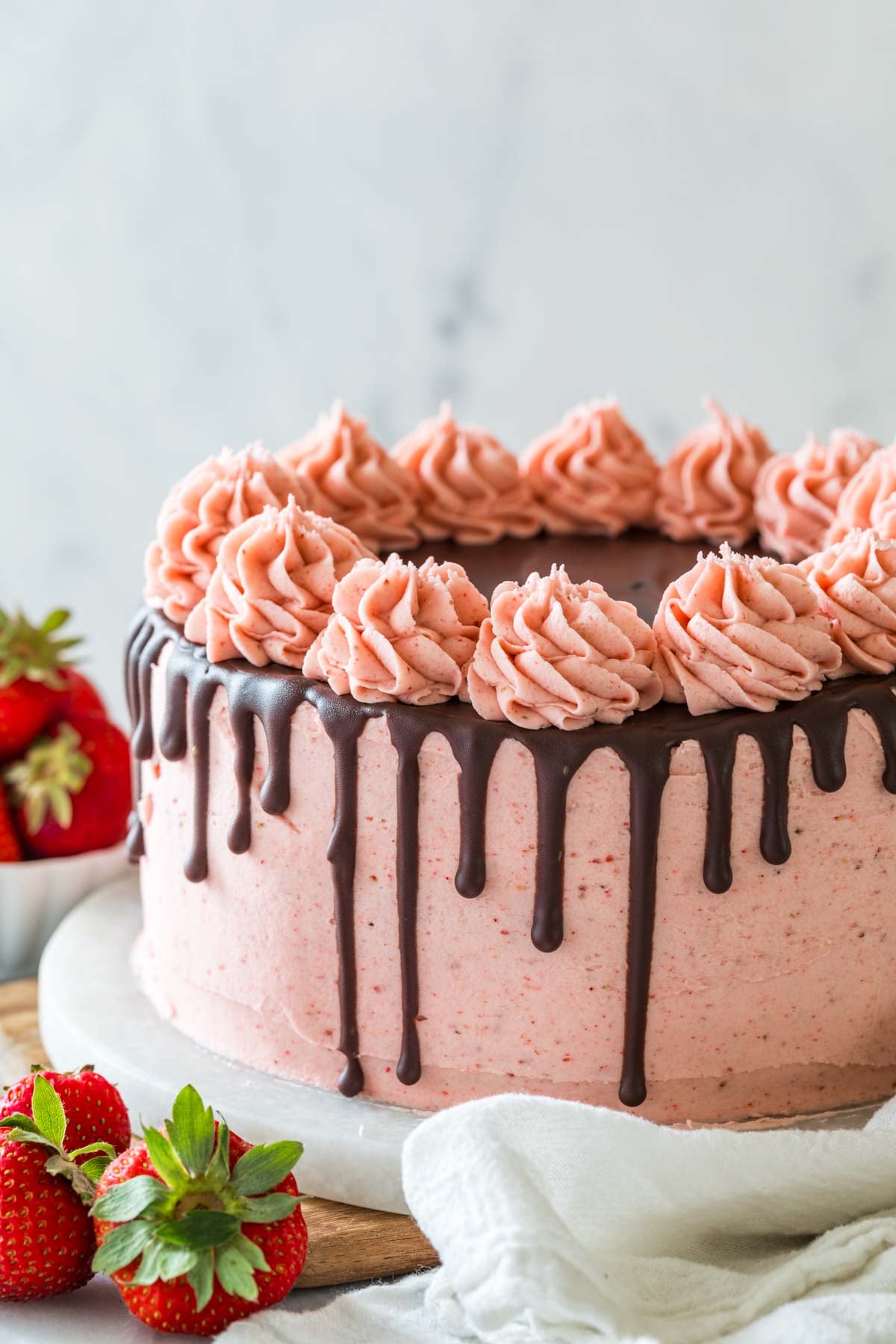 Cake decorated with a pink strawberry frosting and a ganache drip.