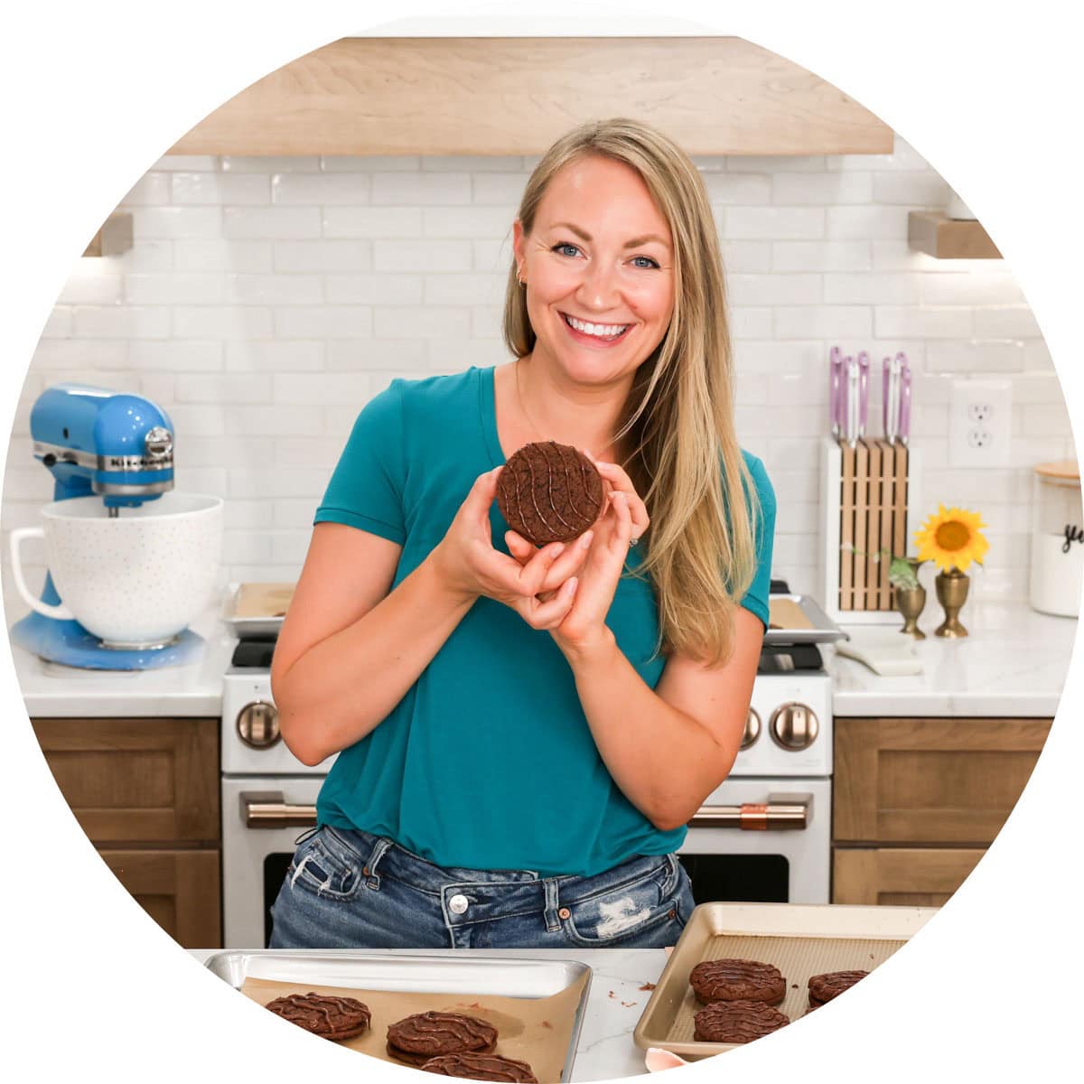 The author Sam Merritt in a blue shirt holding a Fudge Round with blue mixer in background.