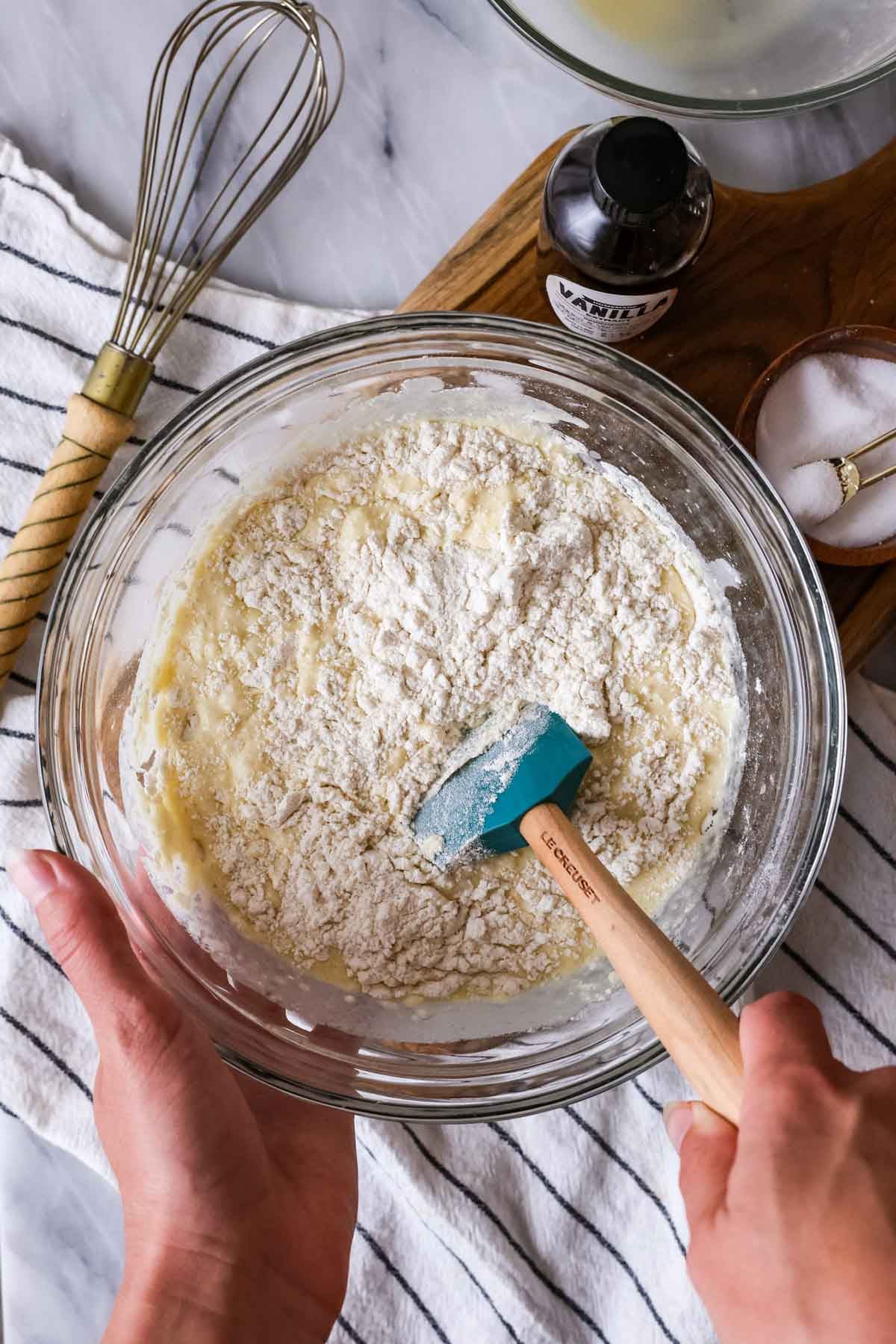 Overhead view of a waffle batter being stirred together with a spatula.