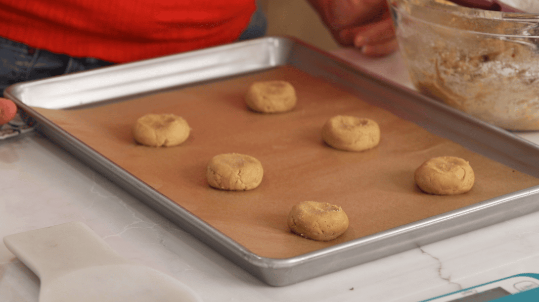 Slightly flattened cookie dough balls on a baking sheet.