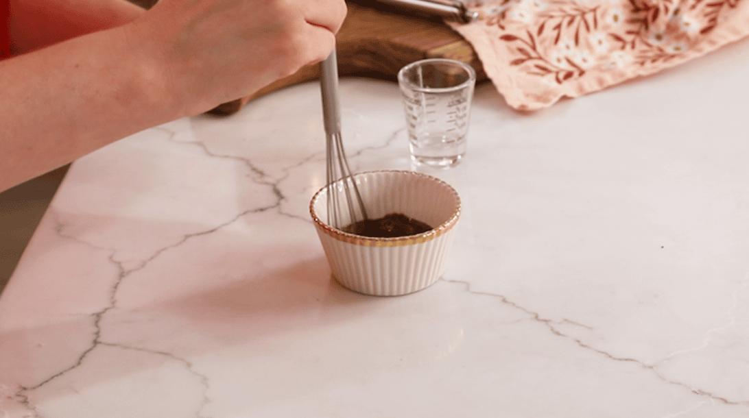 Whisking together water and instant espresso powder.