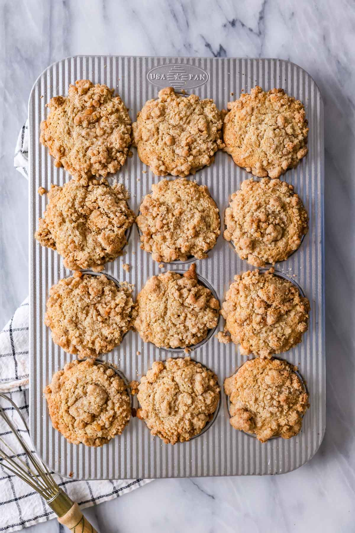 Overhead view of streusel topped muffins in a baking sheet after baking.
