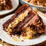 Slice of German chocolate cake on a plate with one bite missing.