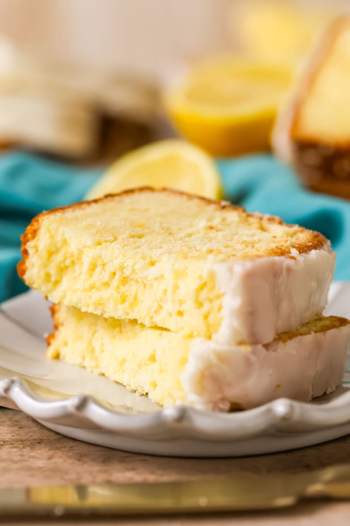 Two halves of a slice of lemon pound cake stacked on top of each other on a plate.