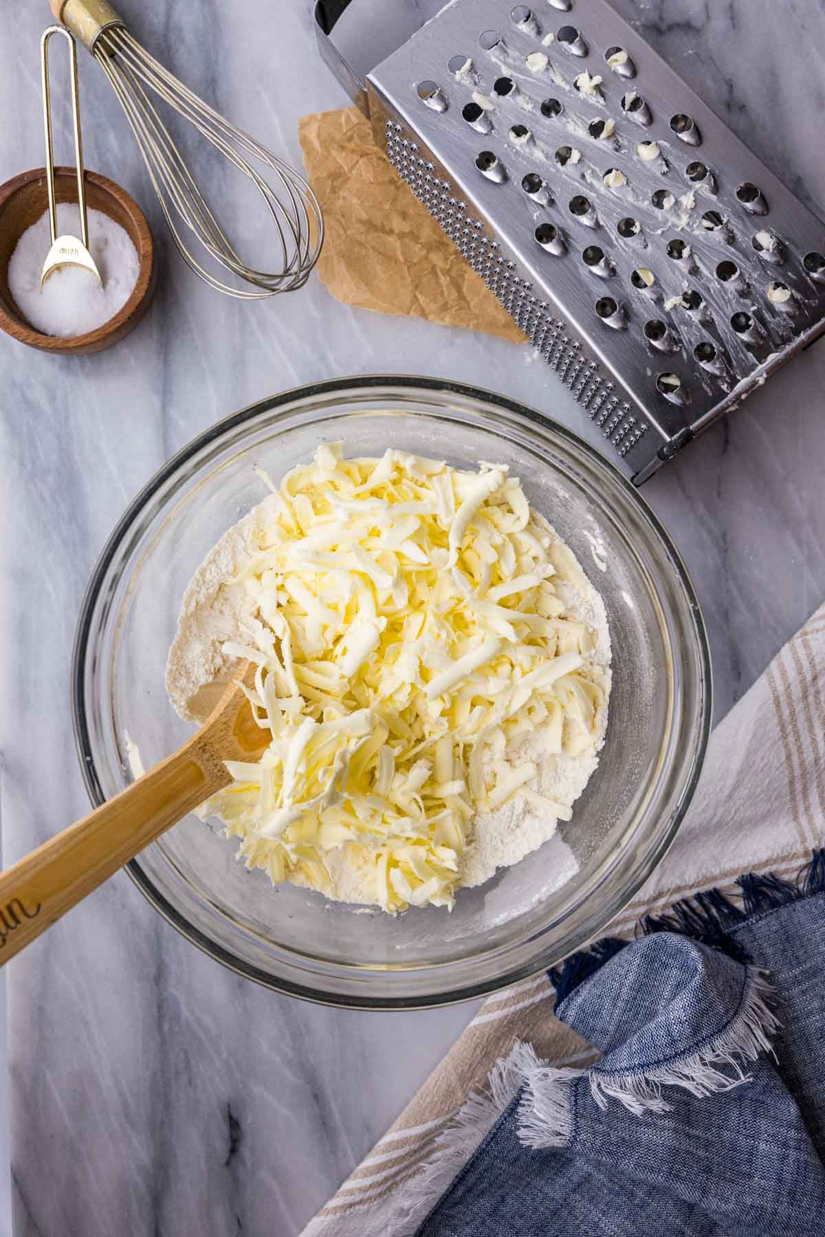Overhead view of a bowl of dry ingredients with grated butter overtop.