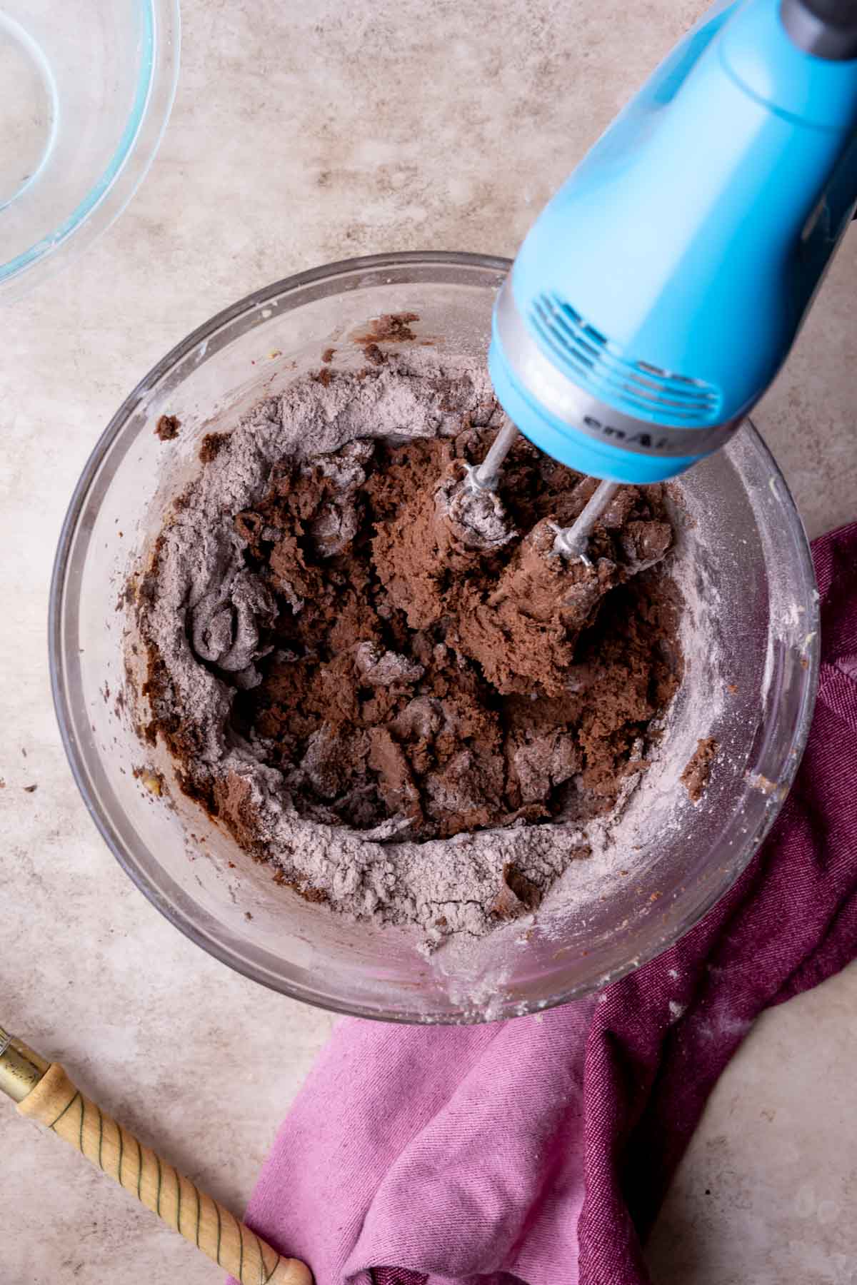 Overhead view of a hand mixer mixing a chocolate cookie dough.