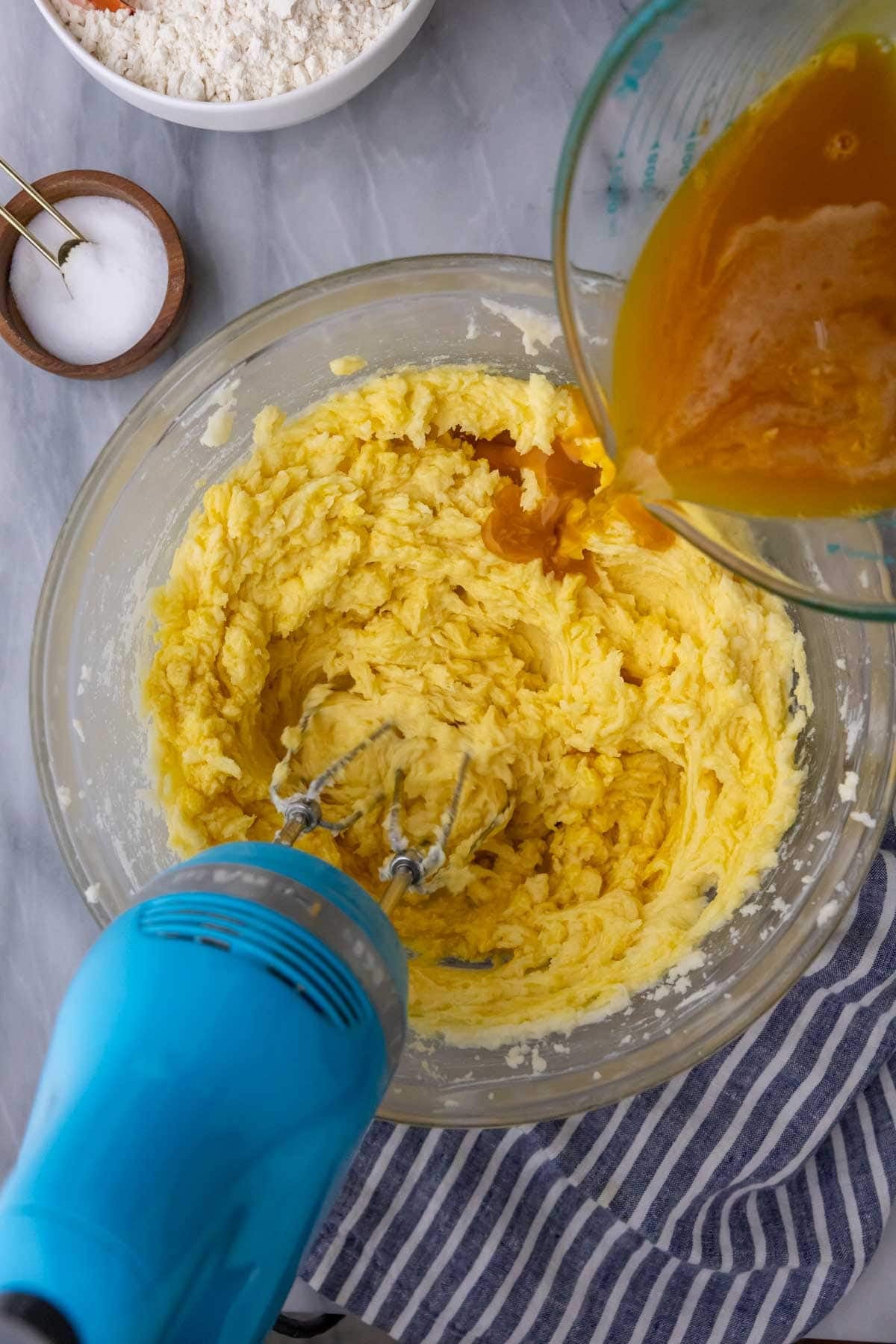 Stirring in eggs/yolks/vanilla into pound cake recipe batter.