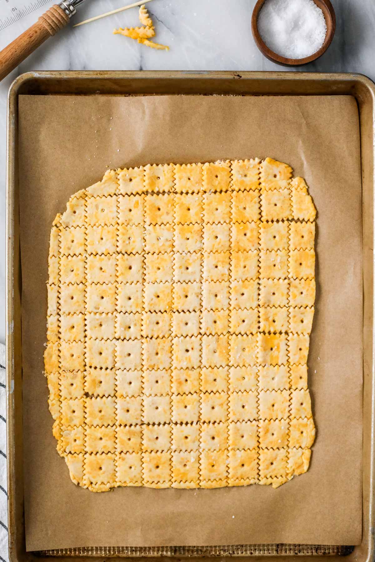 Overhead view of cheese crackers on a baking sheet before baking.