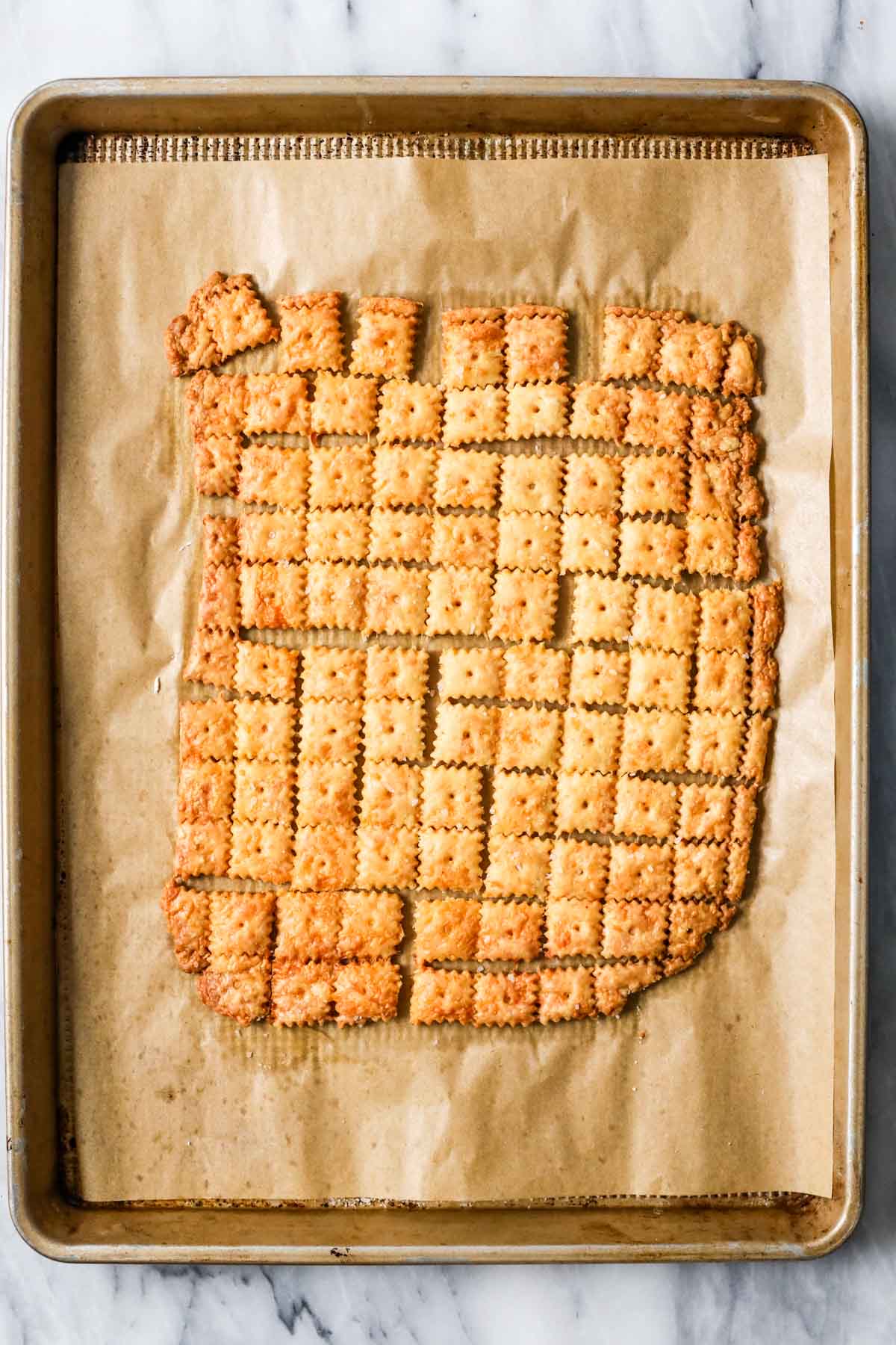 Overhead view of sourdough cheese crackers on a baking sheet after baking.