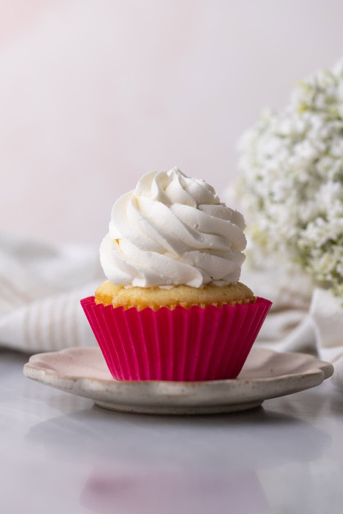 Cupcake topped with a tall swirl of fluffy frosting made with swiss meringue.