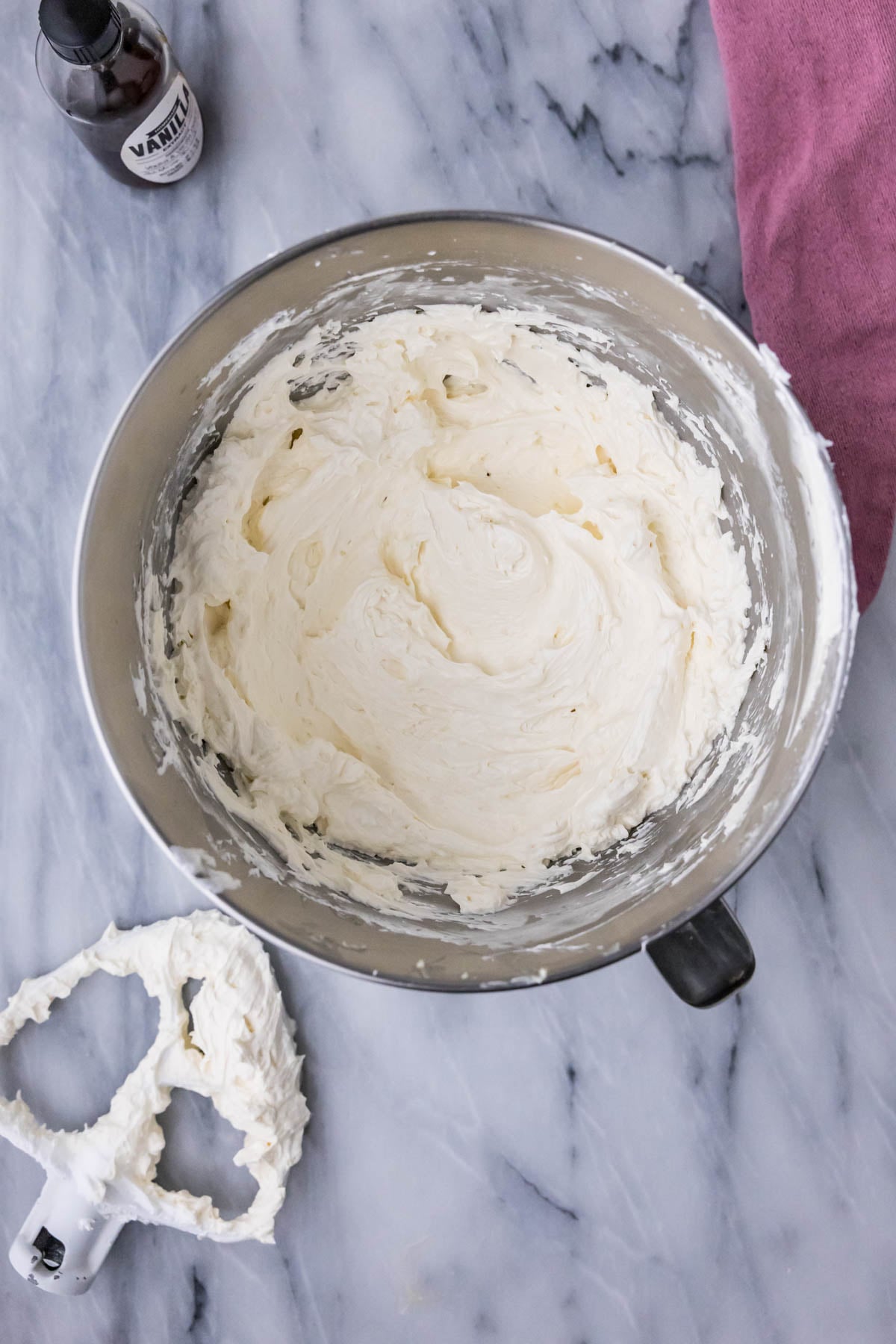 Overhead view of swiss meringue buttercream in a mixer bowl after adding butter.